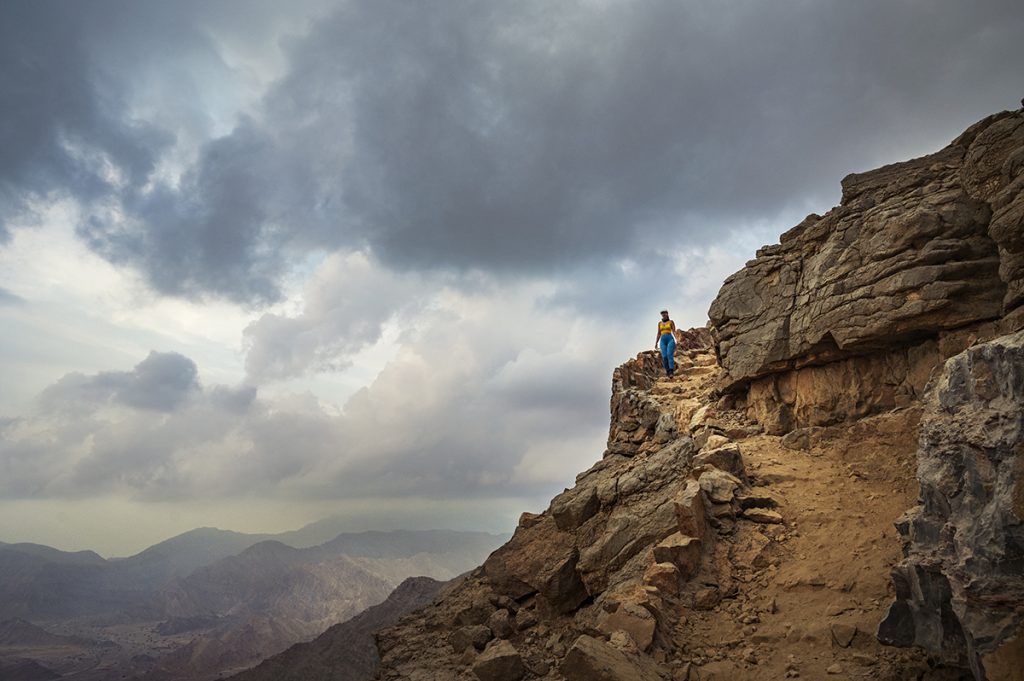 woman on a mountain trail in blue leggings at sunset in uae
