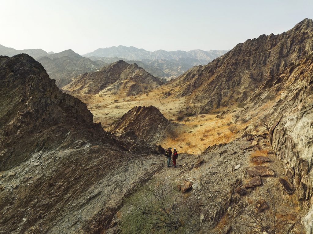 A couple standing on the mountains in Fujeirah, Wadi Tayyibah, UAE, scenery reminds planet Mars