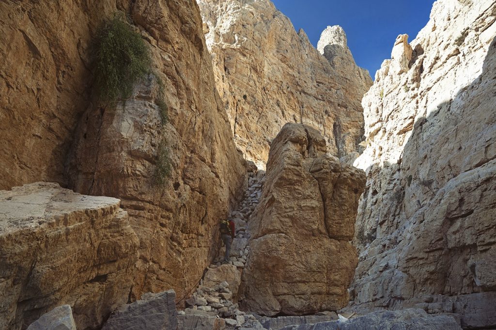 hiking trail in wadi naqab uae with a man climbing stone stairs carved in the mountain