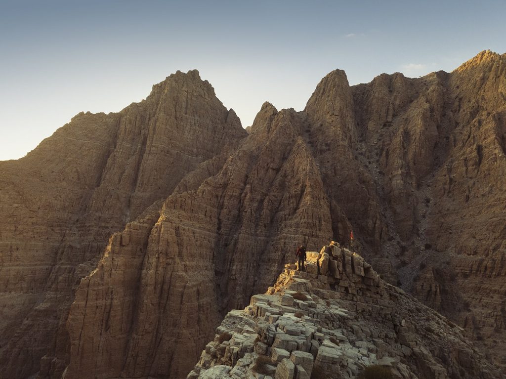 a man standing on the mountain ridge at sunset in ahajar mountains uae