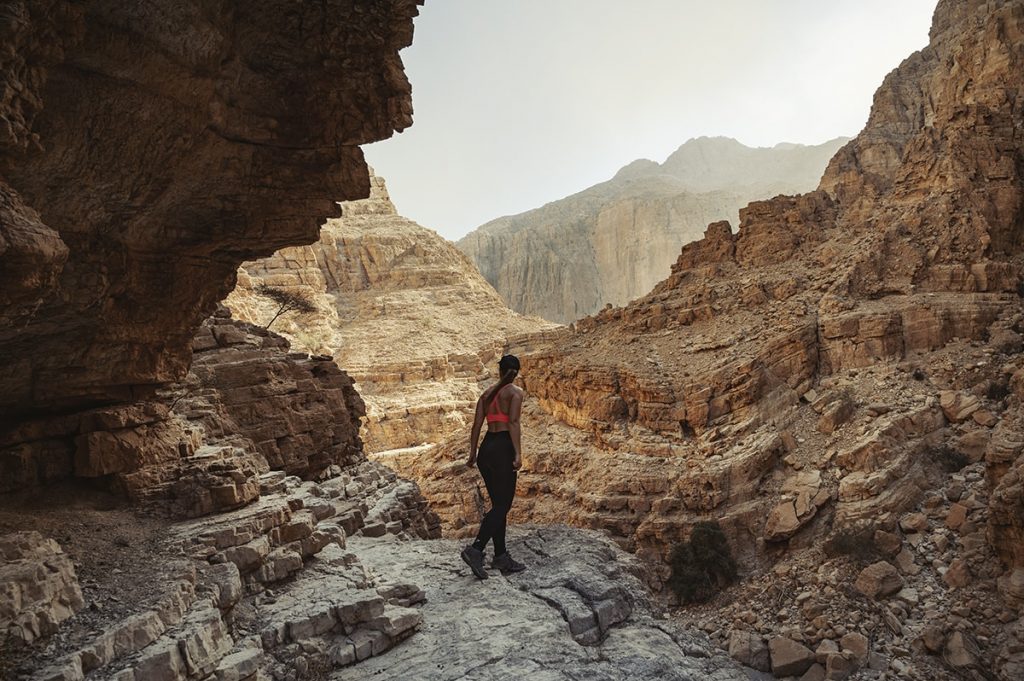 a woman looking out for the way on a rocky mountain trail in wadi naqab uae