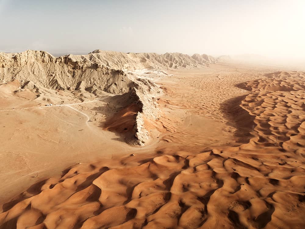 Mleiha eye orange dunes and rugged mountain aerial shot