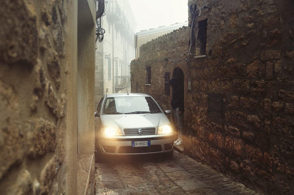 Sicily driving tips- a very narrow road and a car trying to pass with a person giving a way