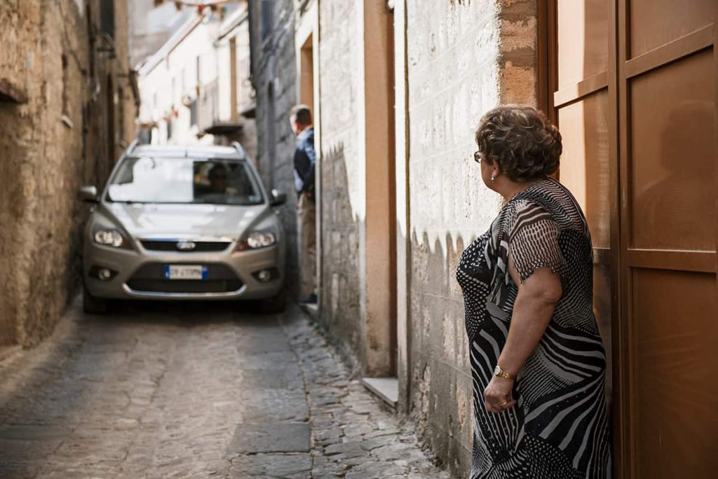 a narrow lane in sicily old town with a car passing