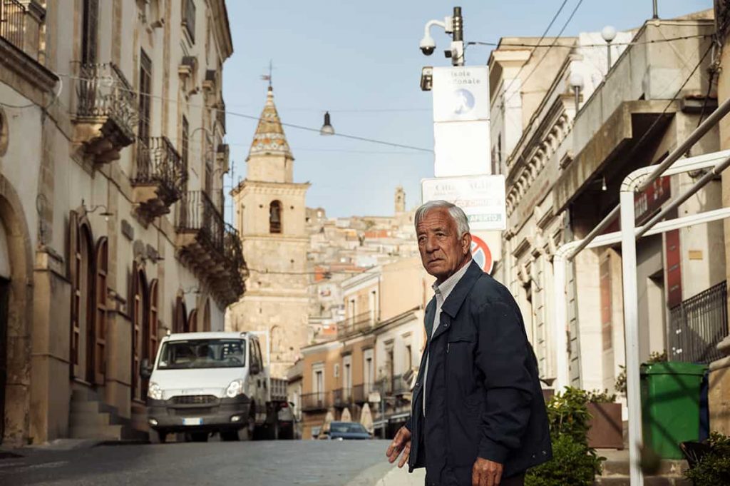 a man crossing a street in agira town in sicily