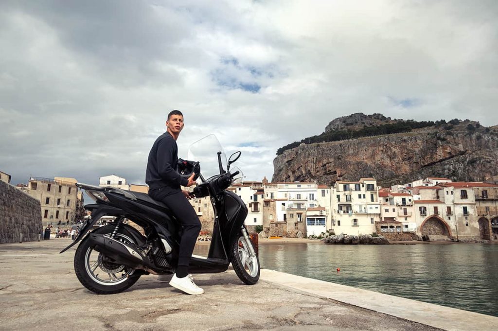 Sicily road trip itinerary- cefalu a guy on motorcycle in old harbor