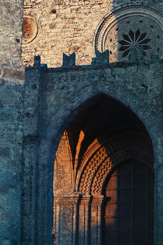 gorthic church arch and gate at sunset in erice town sicily