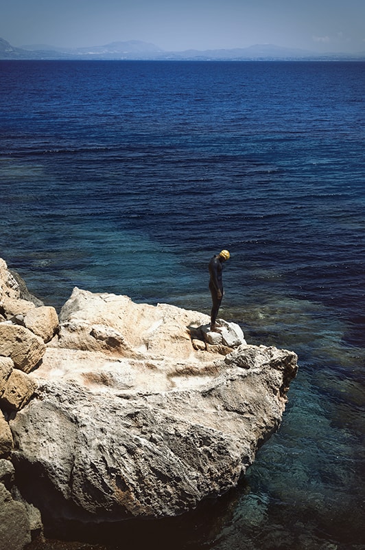bue marino beach man standing on the rock in favignana sicily