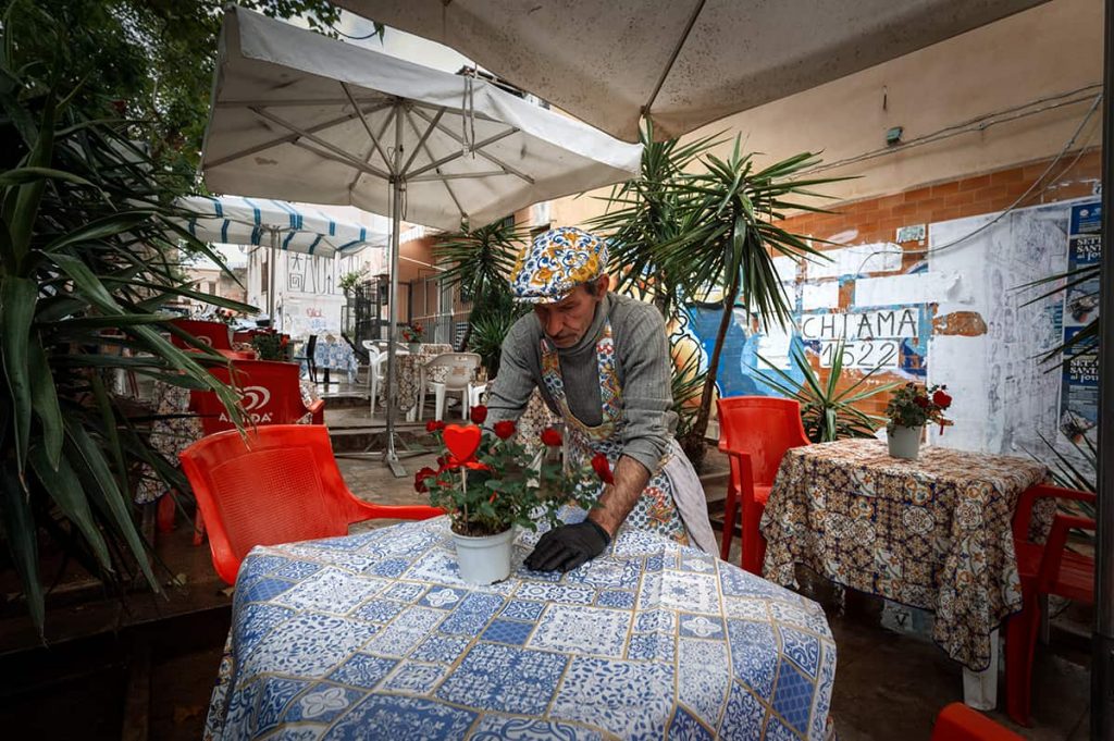 palermo ballaro market man is preparing a table in outdoor restaurant