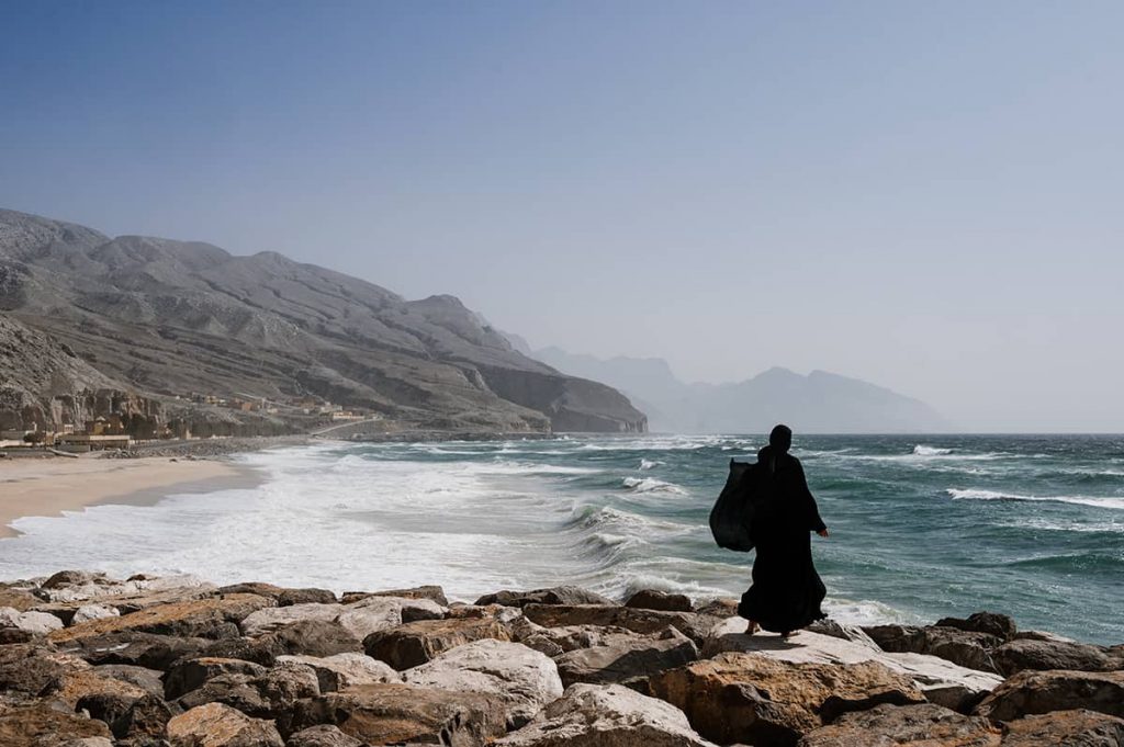 dubai to oman by road a woman in black abaya at the wild beach in musandam