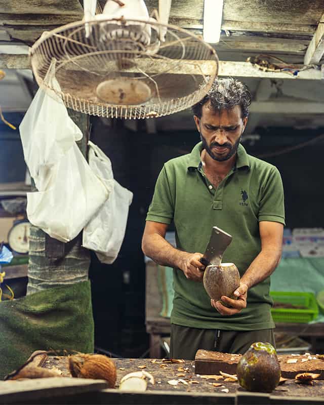 Salalah itinerary and things to do in salalah: a man cutting coconut in the hut of Salalah city