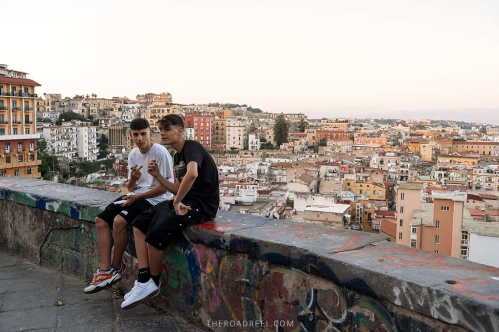 On the way to Sant'Elmo Castle, Naples Italy itinerary, two young guys sitting on the barrier above Naples