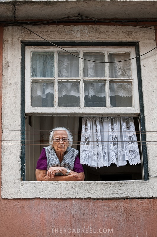 Local senhora in Alfama, Lisbon looking through the window