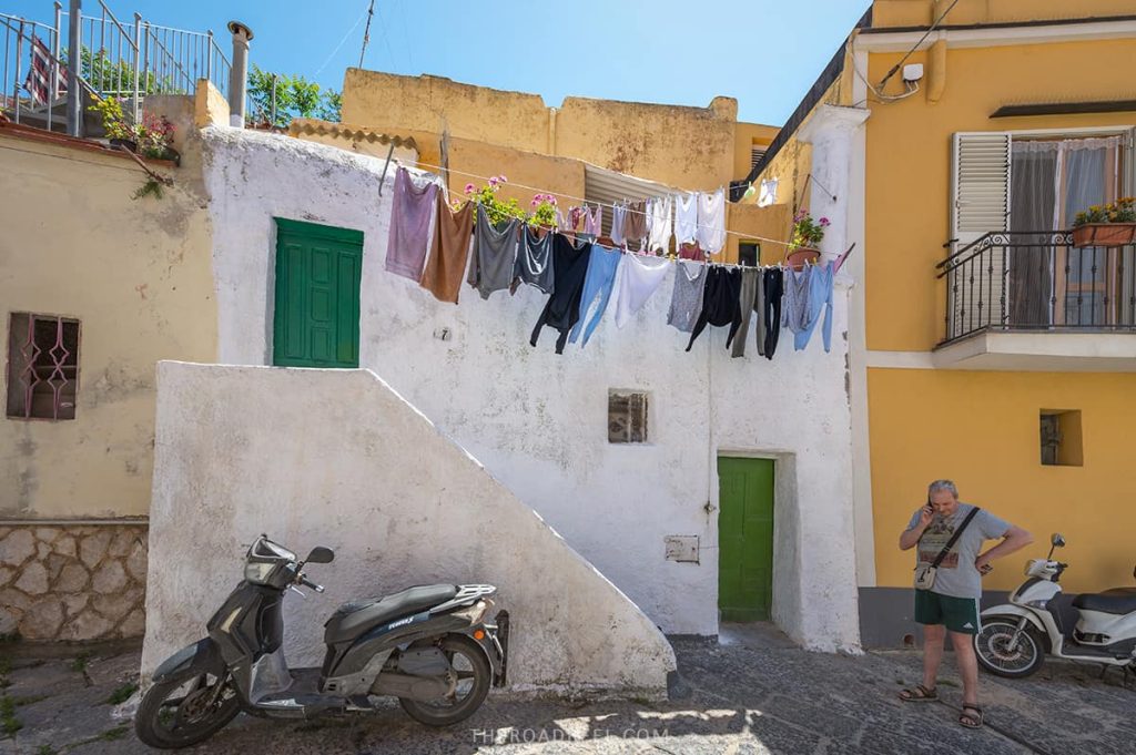 Terra Murata is greeting visitors before they arrive to Procida Island, laundry hanging on the balcony and motorbikes parked