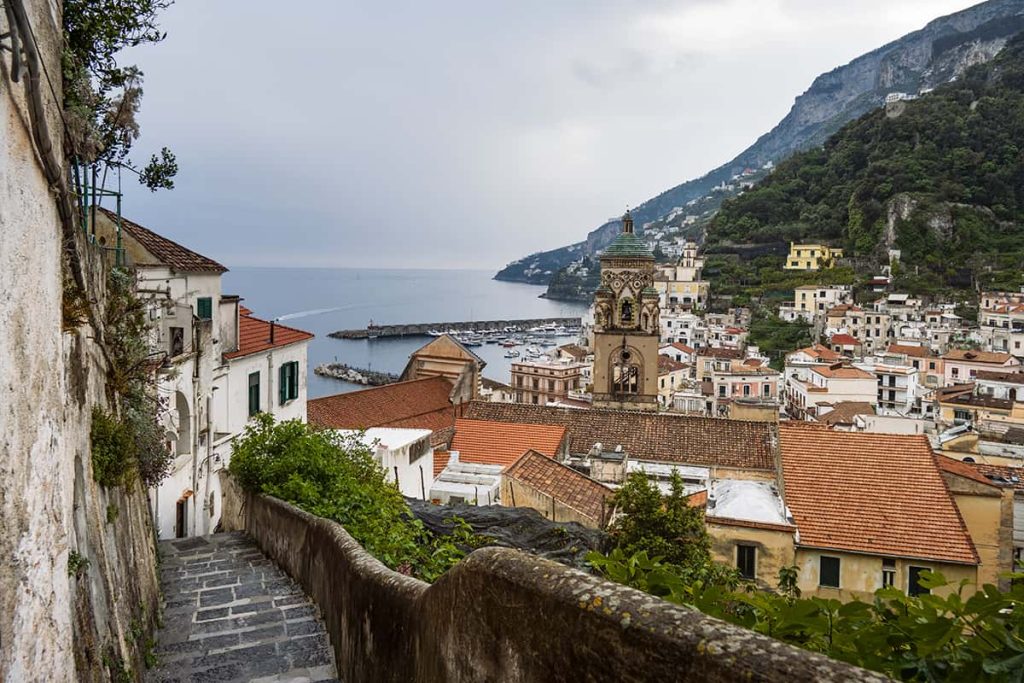 amalfi town from a narrow street with duomo cathedral  bell tower and sea in the distance- south italy itinerary