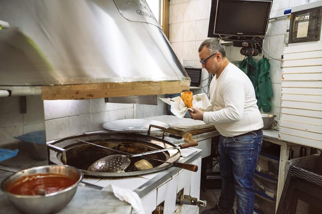 Pizza Frita- one of the best street food you can get in Naples and it is delicious- a man is frying pizza in spanish quarters in his pizzeria