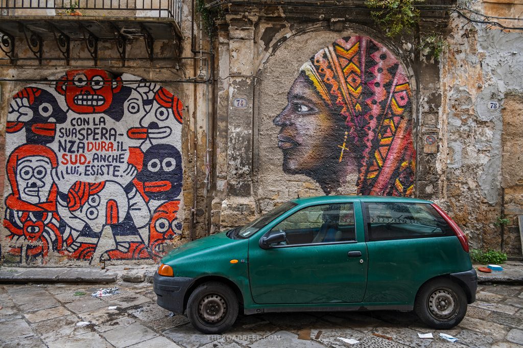 renting a car in Palermo, Sicily: and palermo driving tips, a green car parked in Palermo by a mural with african woman