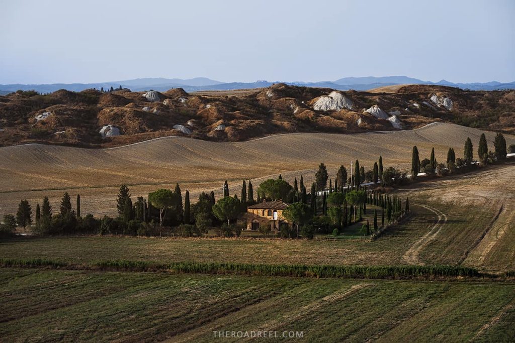 Tuscan countryside with cypress trees and small Tuscany stone house at sunset- renting a car in rome