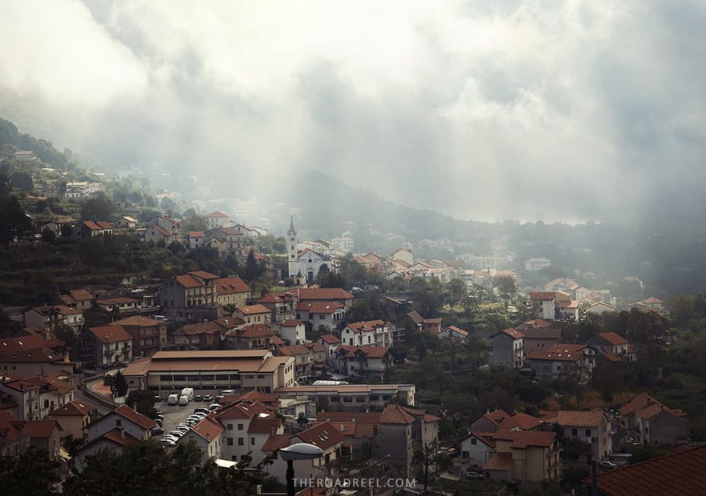 Morning mists weaving through the hillside houses of Agerola, a lesser-known yet enchanting town perched above the Amalfi Coast, with its striking church steeple punctuating the landscape.