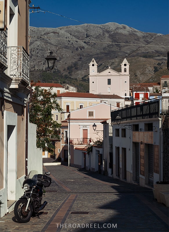 the seaside town of san nicola arcella in calabria, empty street with pink church and a mountain in the distance