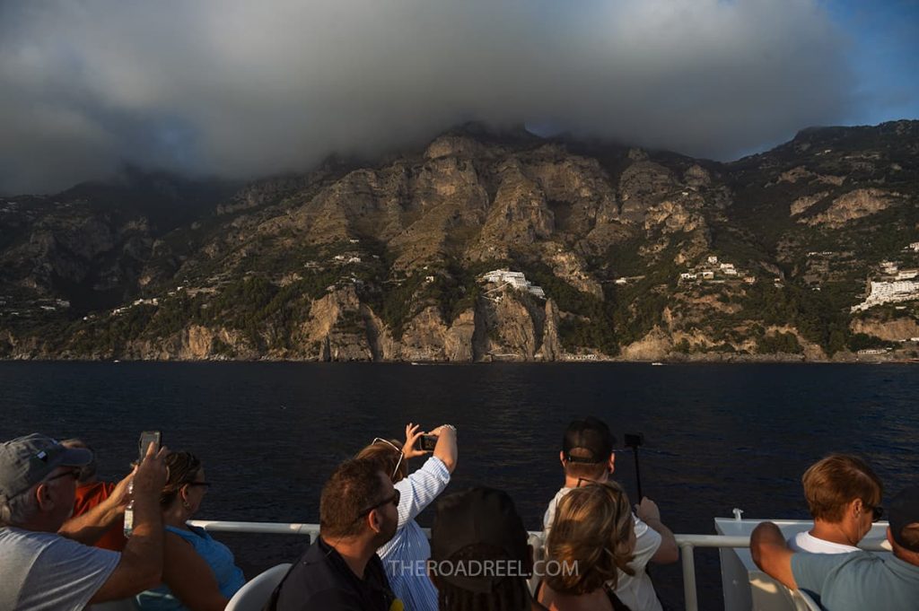 Naples to Amalfi Coast by ferry, people taking pictures from the boat of amalfi coast at sunset