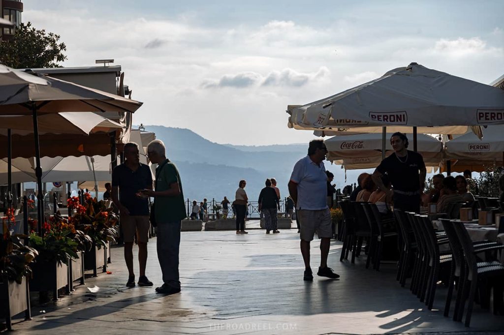 main square in pizzo town in calabria, people are sitting in the cafes in the evening and mountains are visible in the background